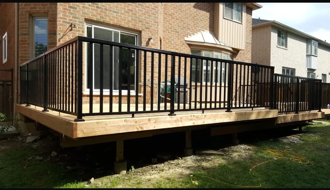 Rear of house after the deck rebuild with a wide cedar deck and black aluminum railing
