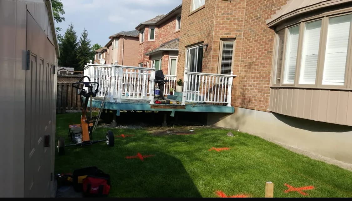 Rear of house before the deck rebuild with the old railing and worn lawn