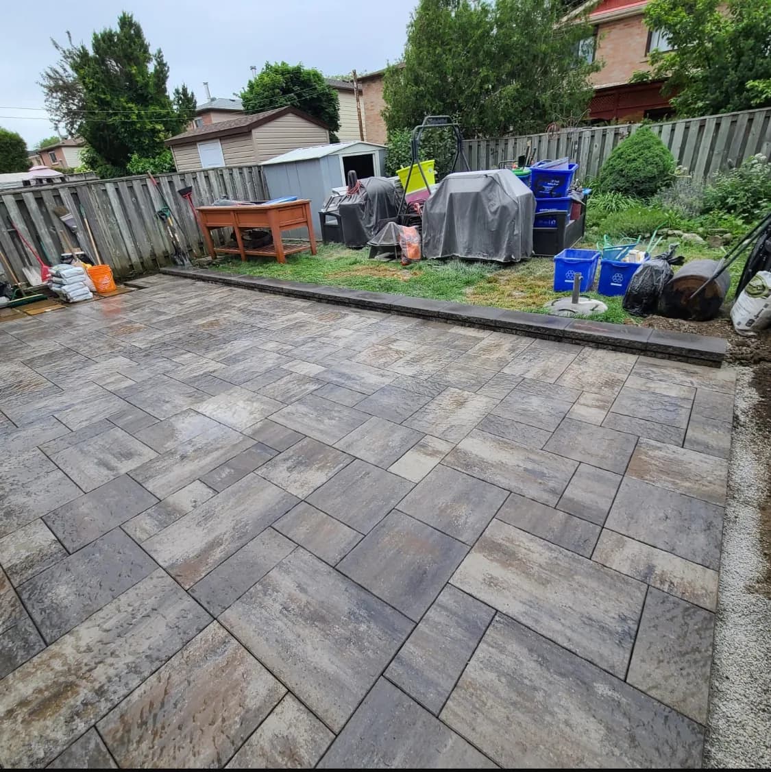 Side of house after hardscaping with a large-format paver patio and defined border