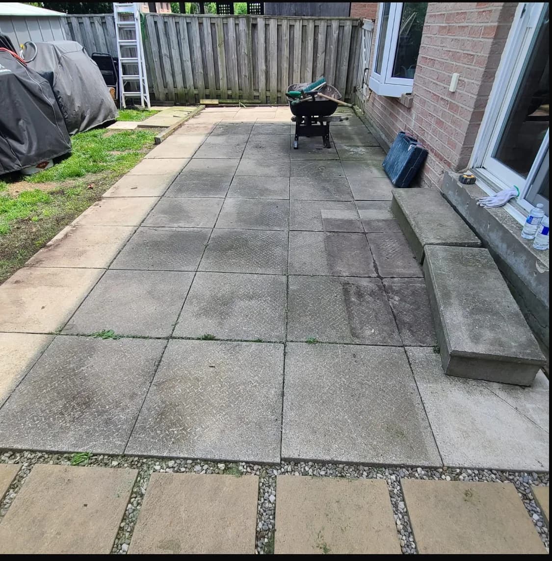 Side of house before hardscaping with cracked, settled concrete slabs and patchy grass