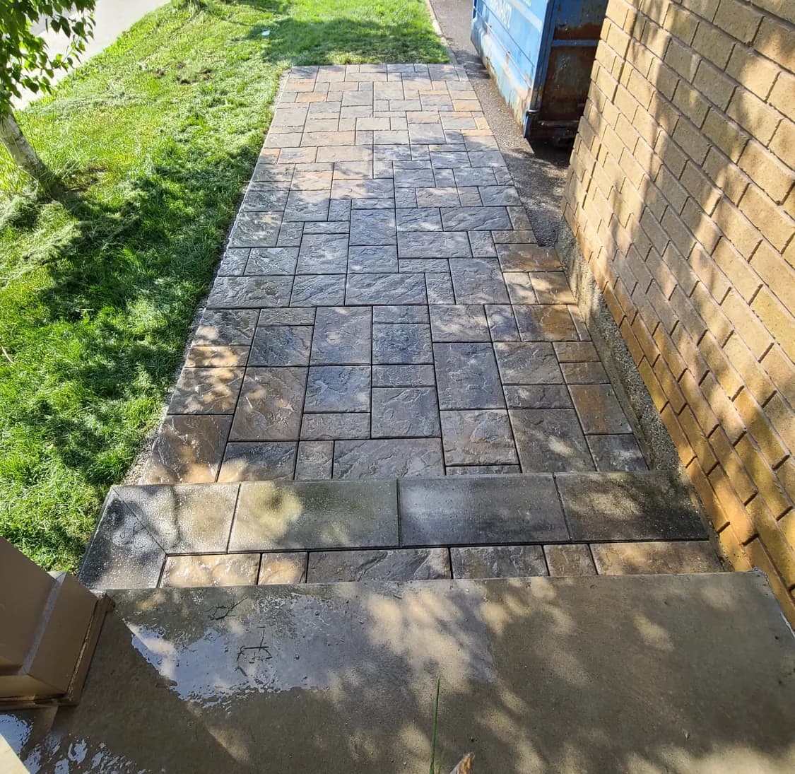 Side yard walkway after hardscaping with new dark-toned pavers laid along the house