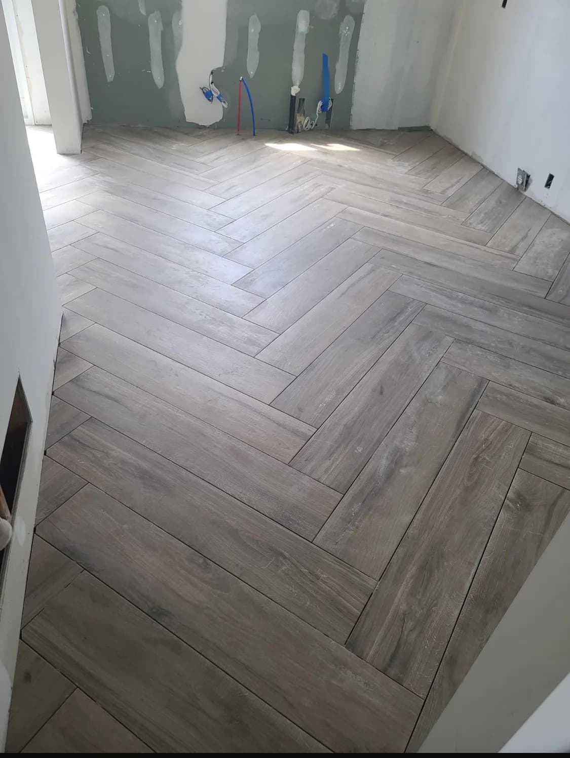 Light wood herringbone flooring installation in progress with clean pattern alignment